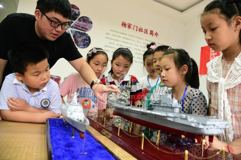 2020年7月11日,在江蘇省鎮江市楊家門社區,江蘇科技大學志愿者通過“遼寧號”航模及其驅逐艦模型向小朋友介紹海防知識。