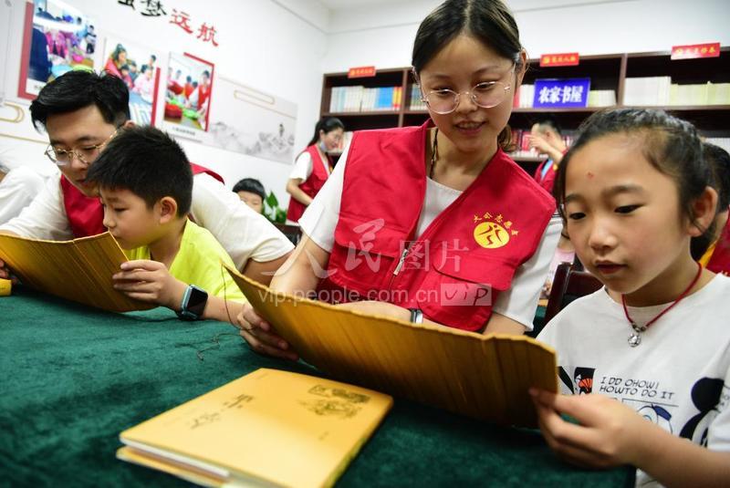 2020年7月19日,在江蘇省鎮江市金江社區農家書屋,江蘇科技大學志愿者在指導小朋友誦讀經典詩文。